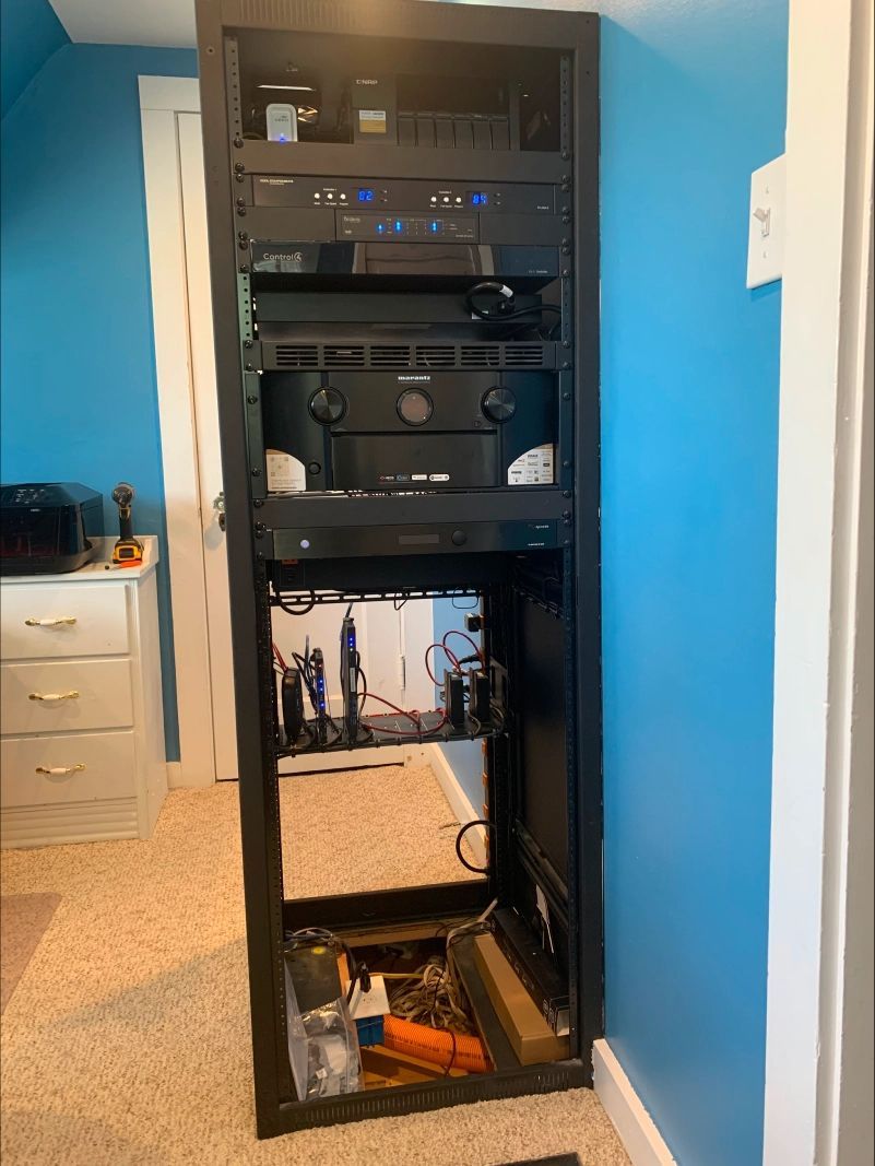 Black AV equipment rack in a room; contains various electronic components.