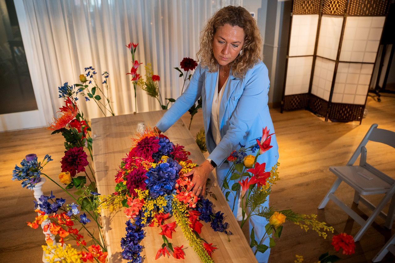 Santine van Leeuwen van Silk Flower Store schikt een kistbedekking van zijden bloemen in rood, blauw en geel