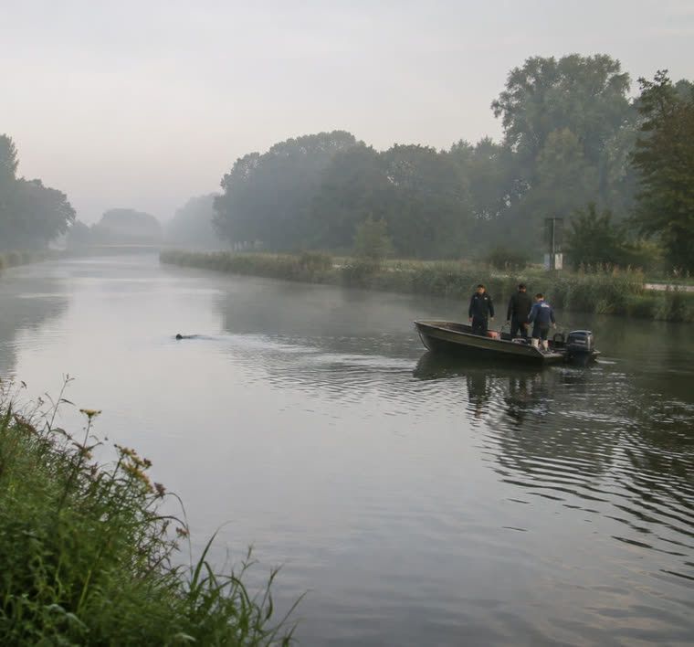 Politie en duikers bij een vondst in het water langs een kanaal in de vroege ochtend