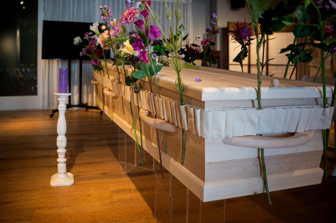 Bloemenband van zijden bloemen rondom een lichte houten kist, samengesteld door Silk Flower Store