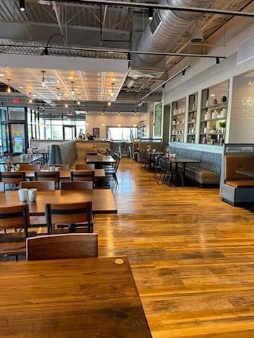 Modern restaurant interior with wooden tables, bar seating, and polished wood floors