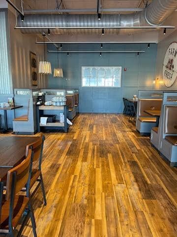 Empty café interior with blue walls, wood floors, and seating along both sides