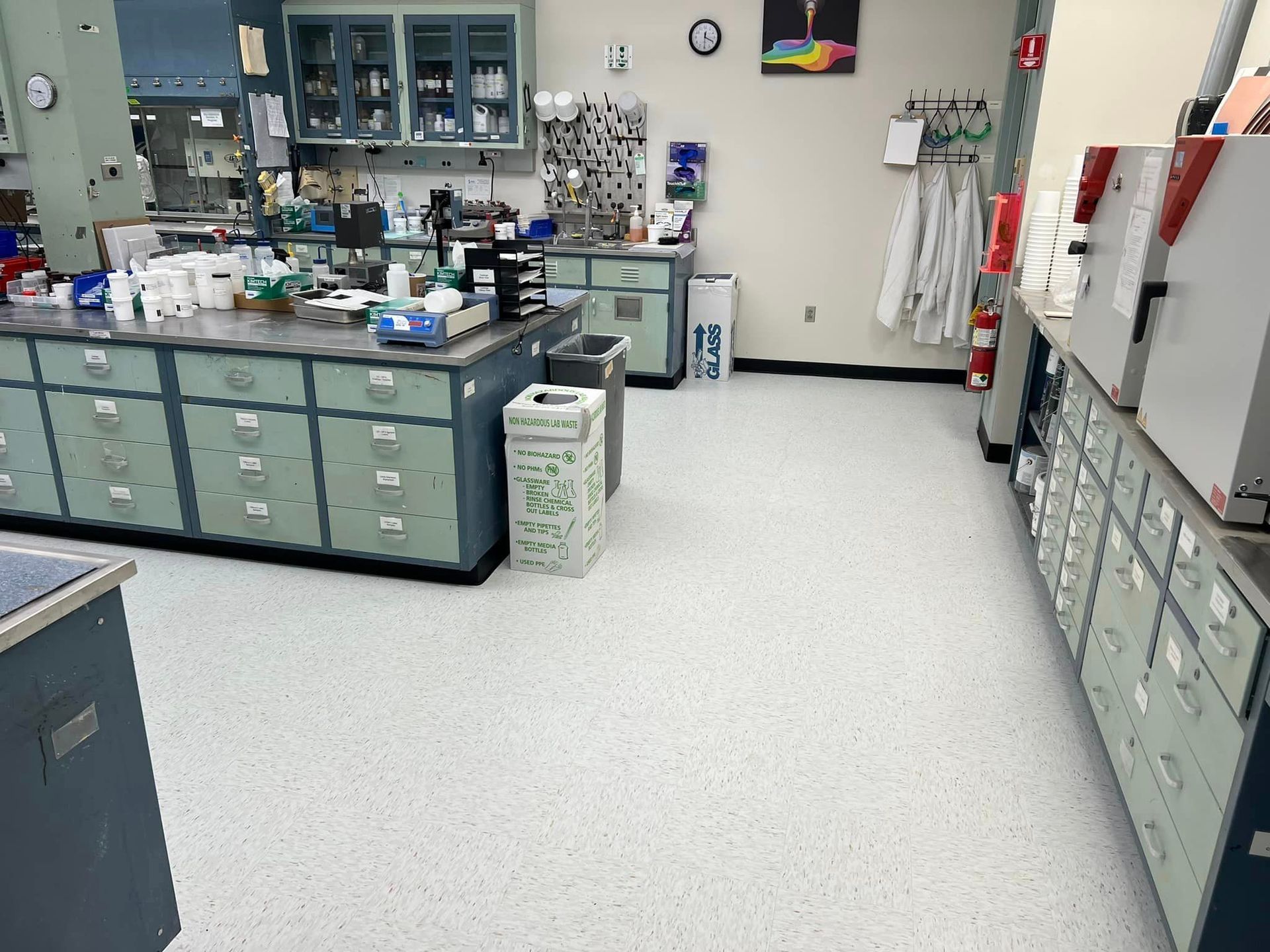Laboratory with workbenches, cabinets, and shelves of supplies in a bright room