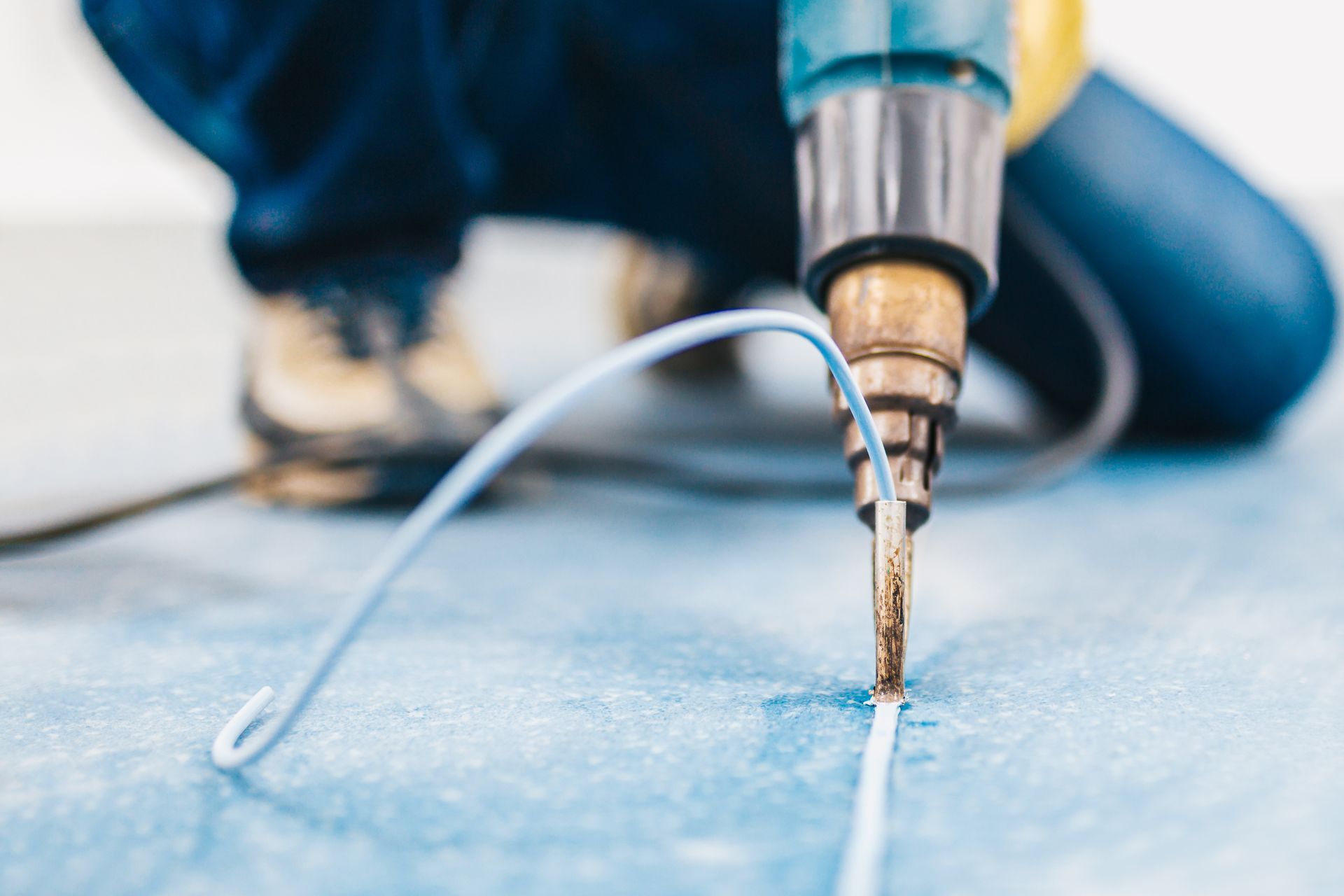 Drill bit cutting a white line on blue floor during repair work
