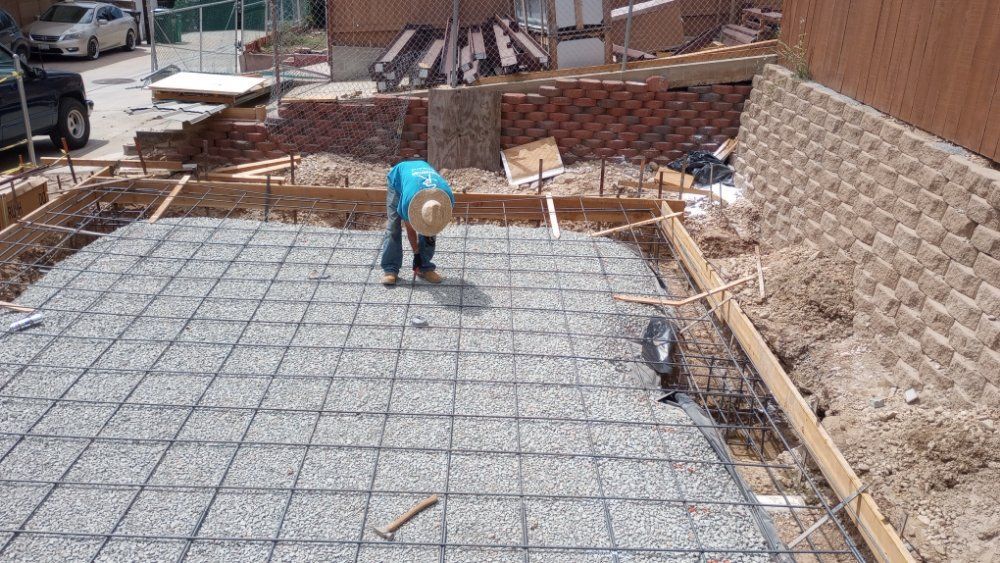 A construction worker is kneeling on a concrete slab.
