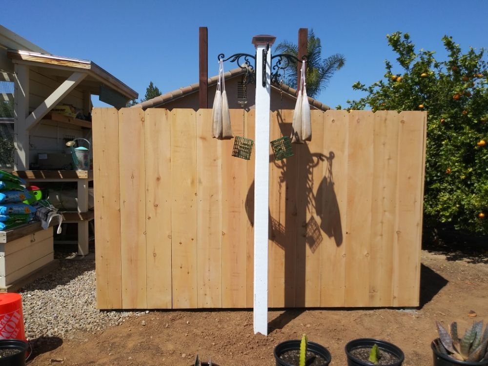A wooden fence with a white pole in front of it