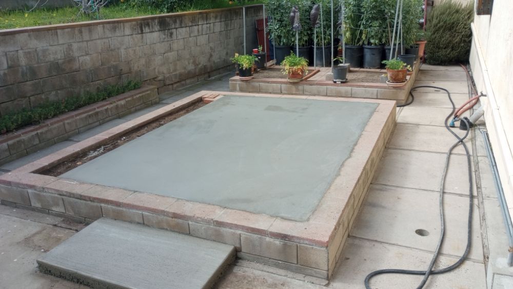 A concrete planter is being built in a backyard.