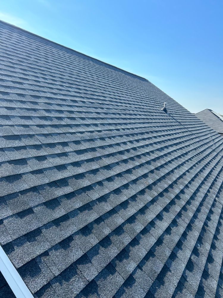 Blue shingle roof with a steep slope against a clear blue sky