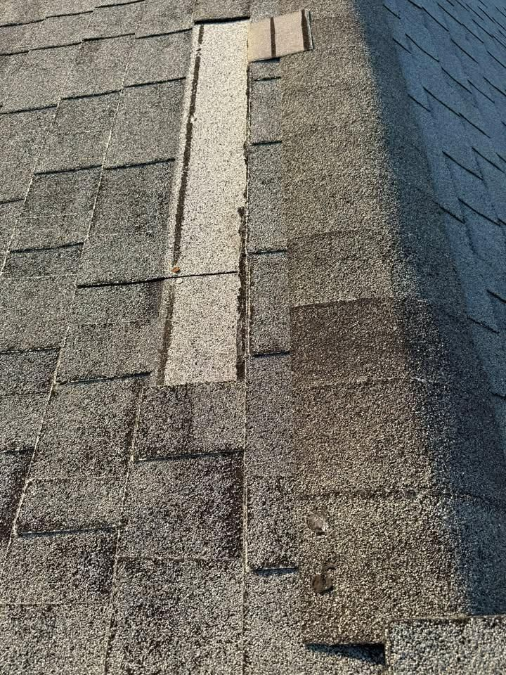 Roof shingles with a vertical strip of lighter patching or repair along the ridge area.