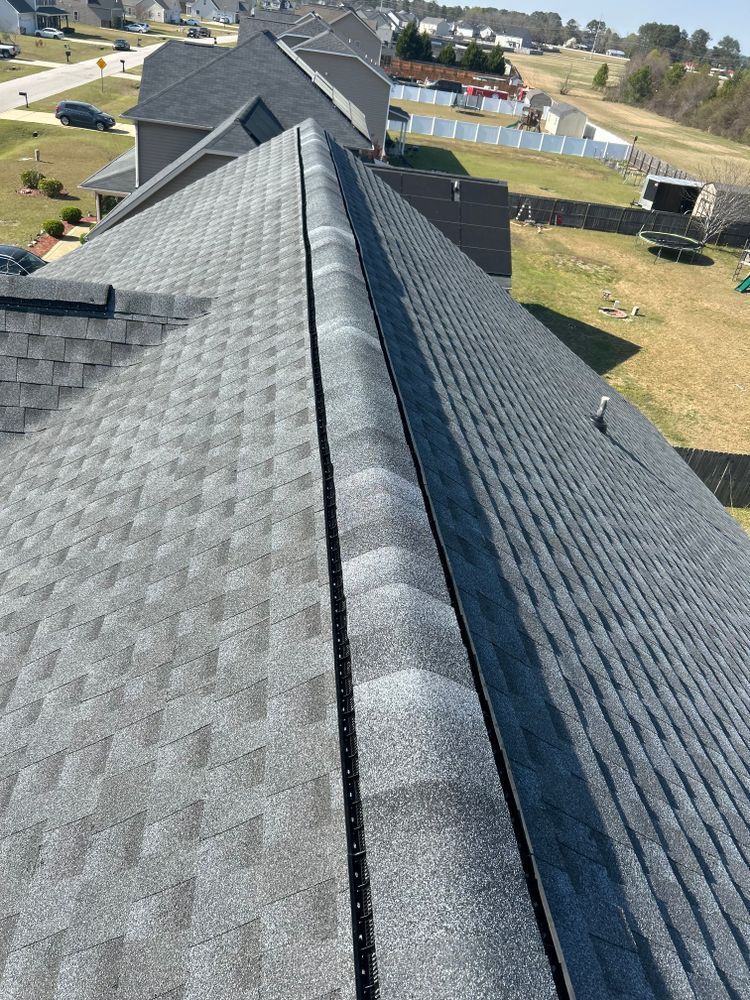 A view from above showing a dark gray shingled roof with a prominent ridgeline and ventilation strip.
