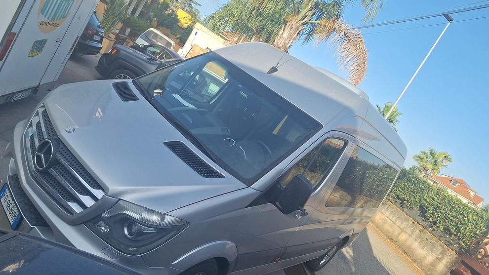 Furgone Mercedes-Benz Sprinter color argento parcheggiato all'aperto in una giornata di sole, vista angolata.