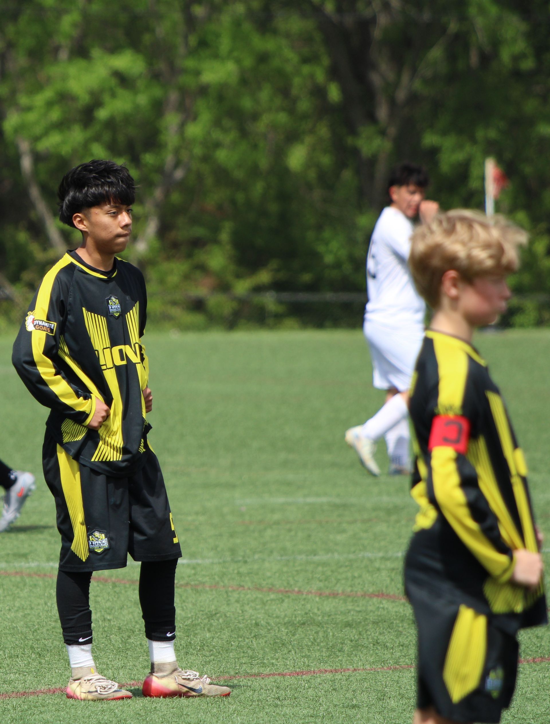 Youth soccer players in black-and-yellow uniforms standing on a grassy field during a game