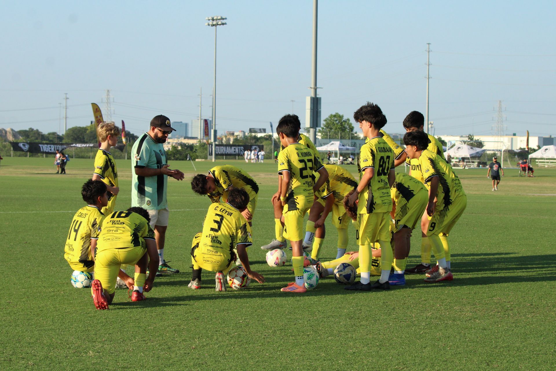 Soccer team in yellow uniforms huddles on a field during practice or a match