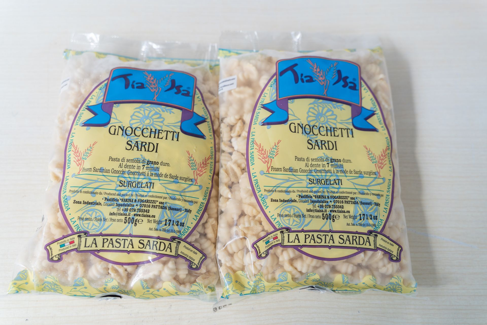 Due sacchetti di pasta sarda biologica in confezione gialla con etichette blu su sfondo bianco