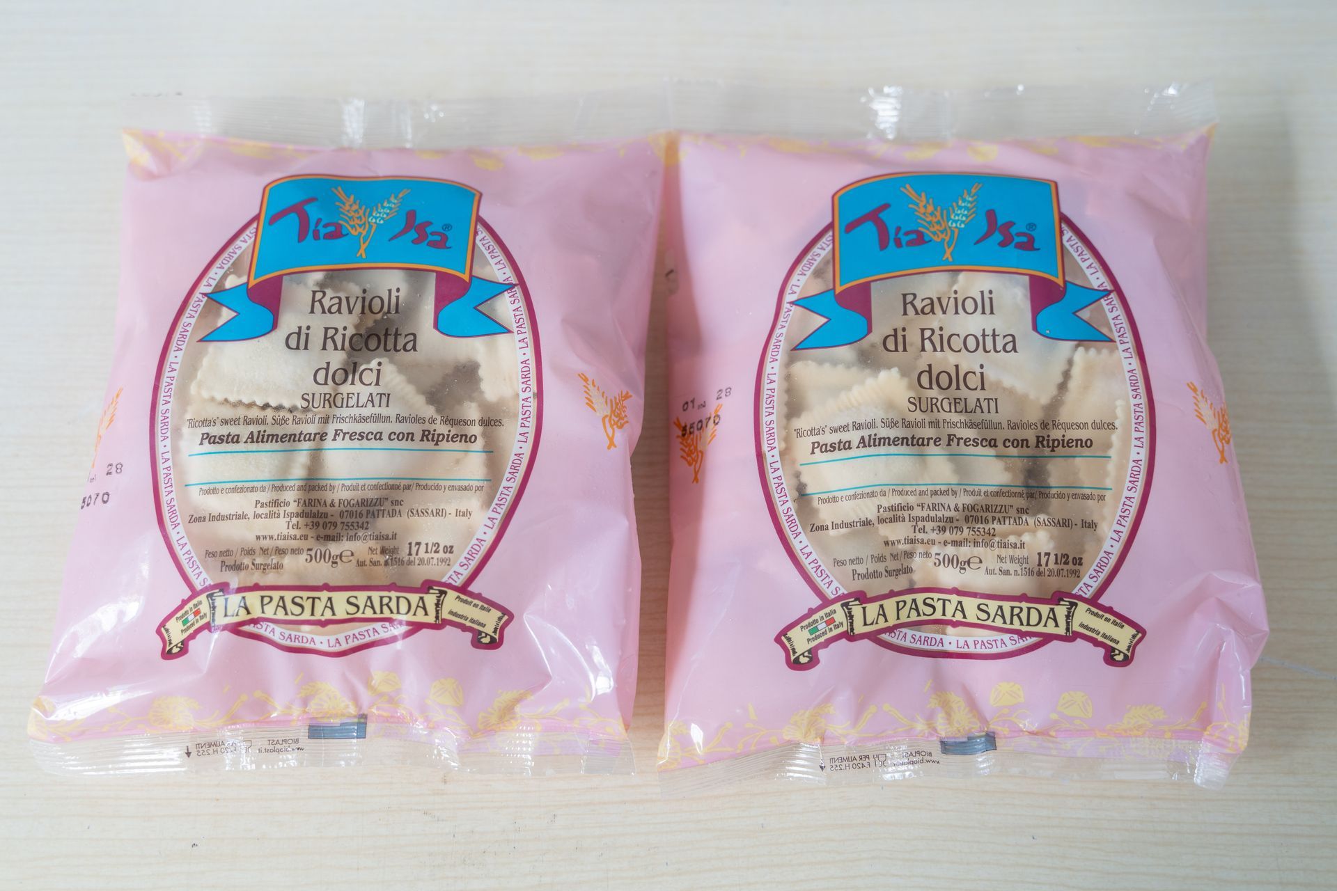 Confezione di ravioli quadrati alla ricotta in un sacchetto di plastica trasparente con un’etichetta viola su sfondo bianco
