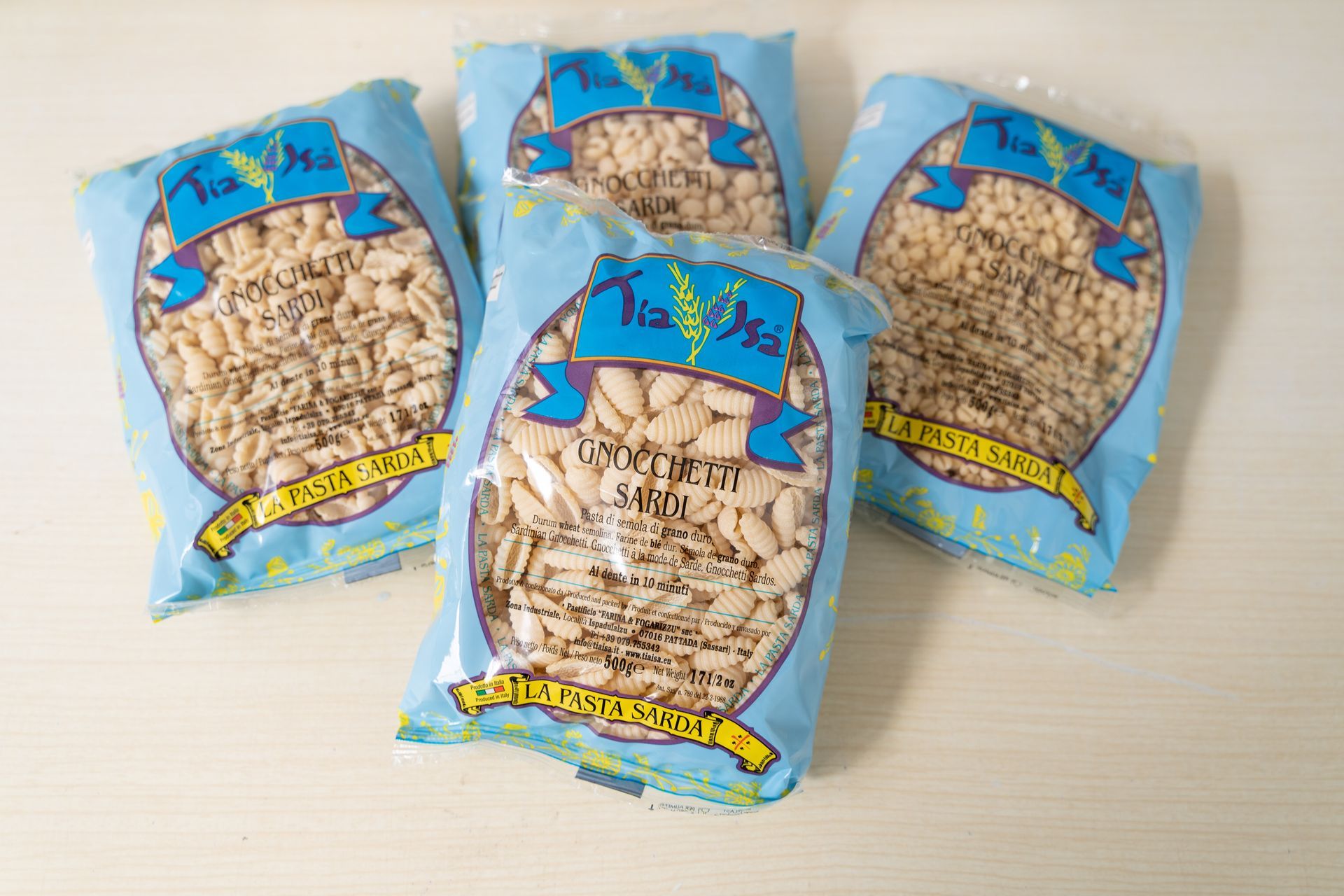Quattro sacchetti blu di snack ripieni di cereali soffiati su una superficie chiara
