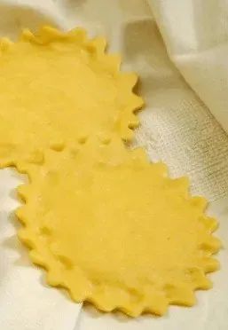 Due quadrati di pasta per ravioli crudi su uno sfondo di stoffa chiara