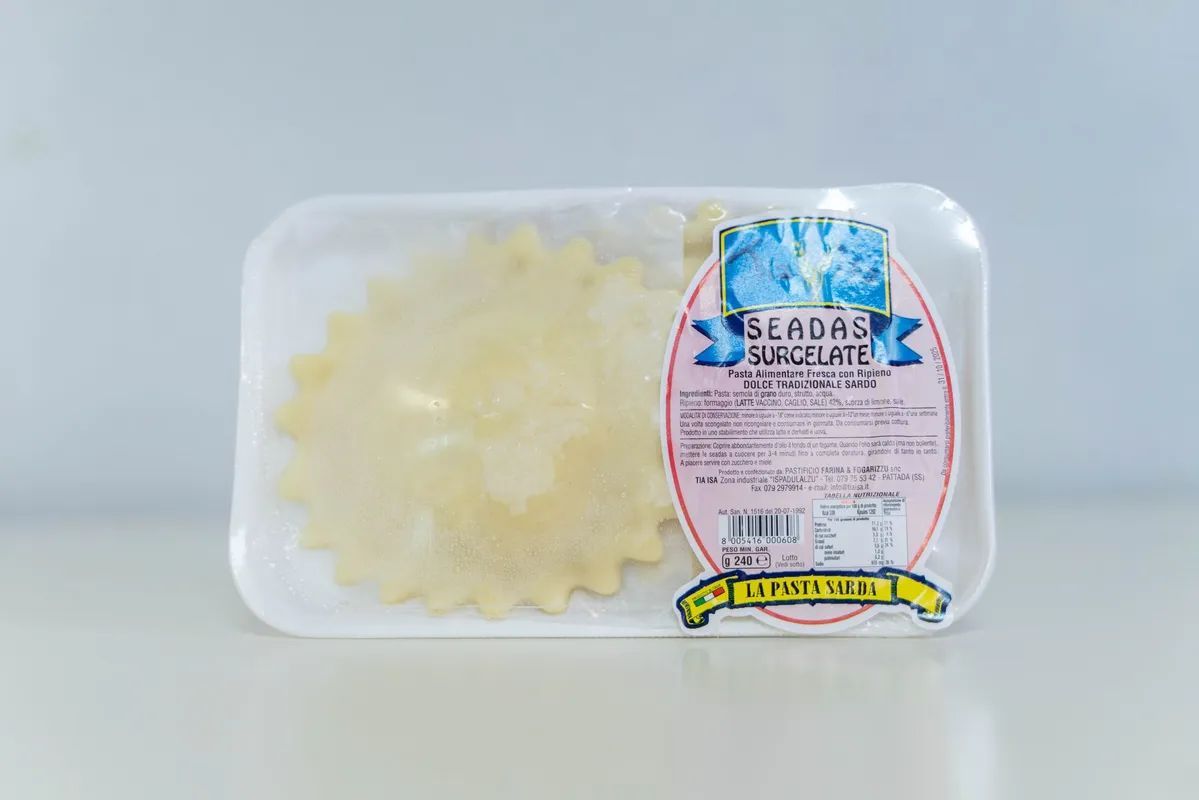 Vassoio di plastica trasparente con una saponetta floreale giallo pallido accanto a una saponetta blu con etichetta rosa