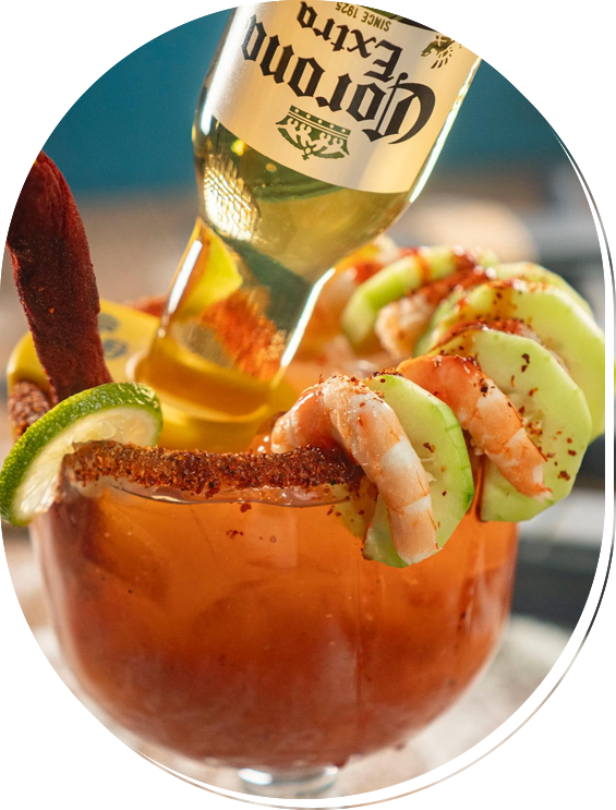 A Corona beer bottle in a glass with shrimp, cucumber, and lime.