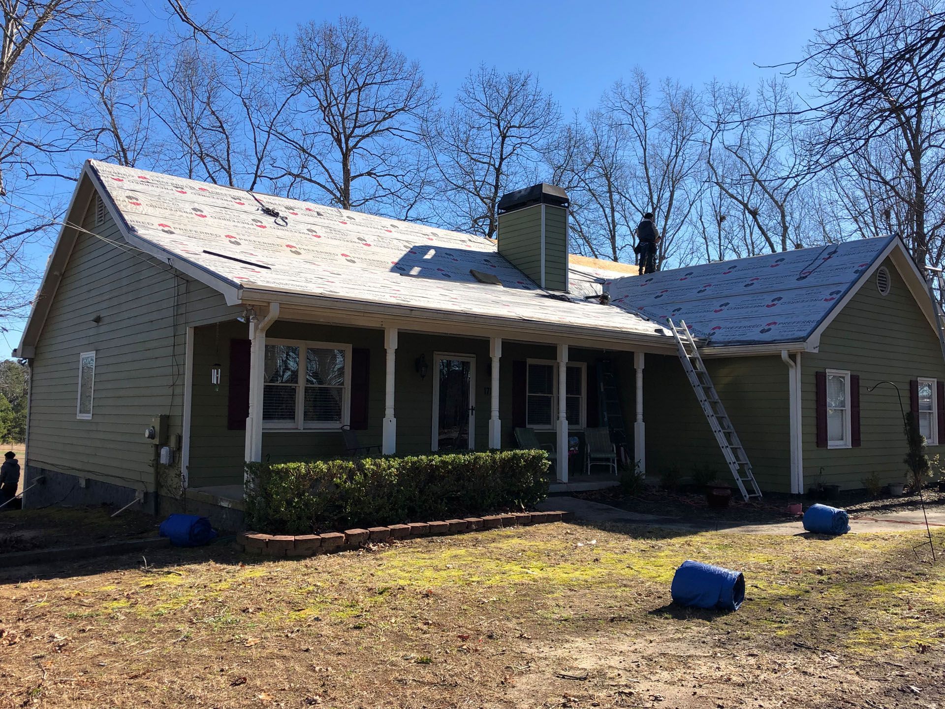 A green house with a white roof and a porch.