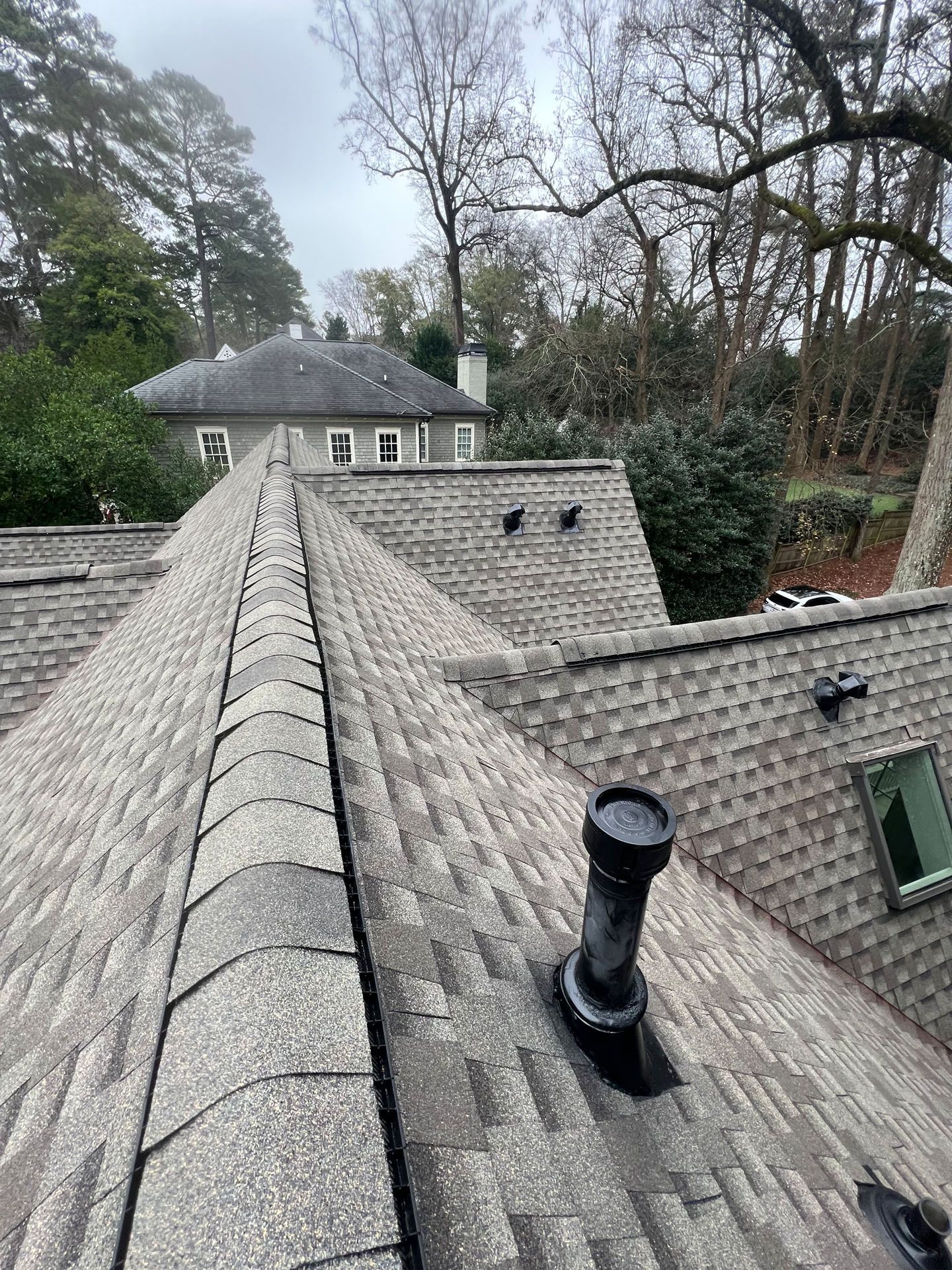 A roof with a chimney on it and a house in the background.