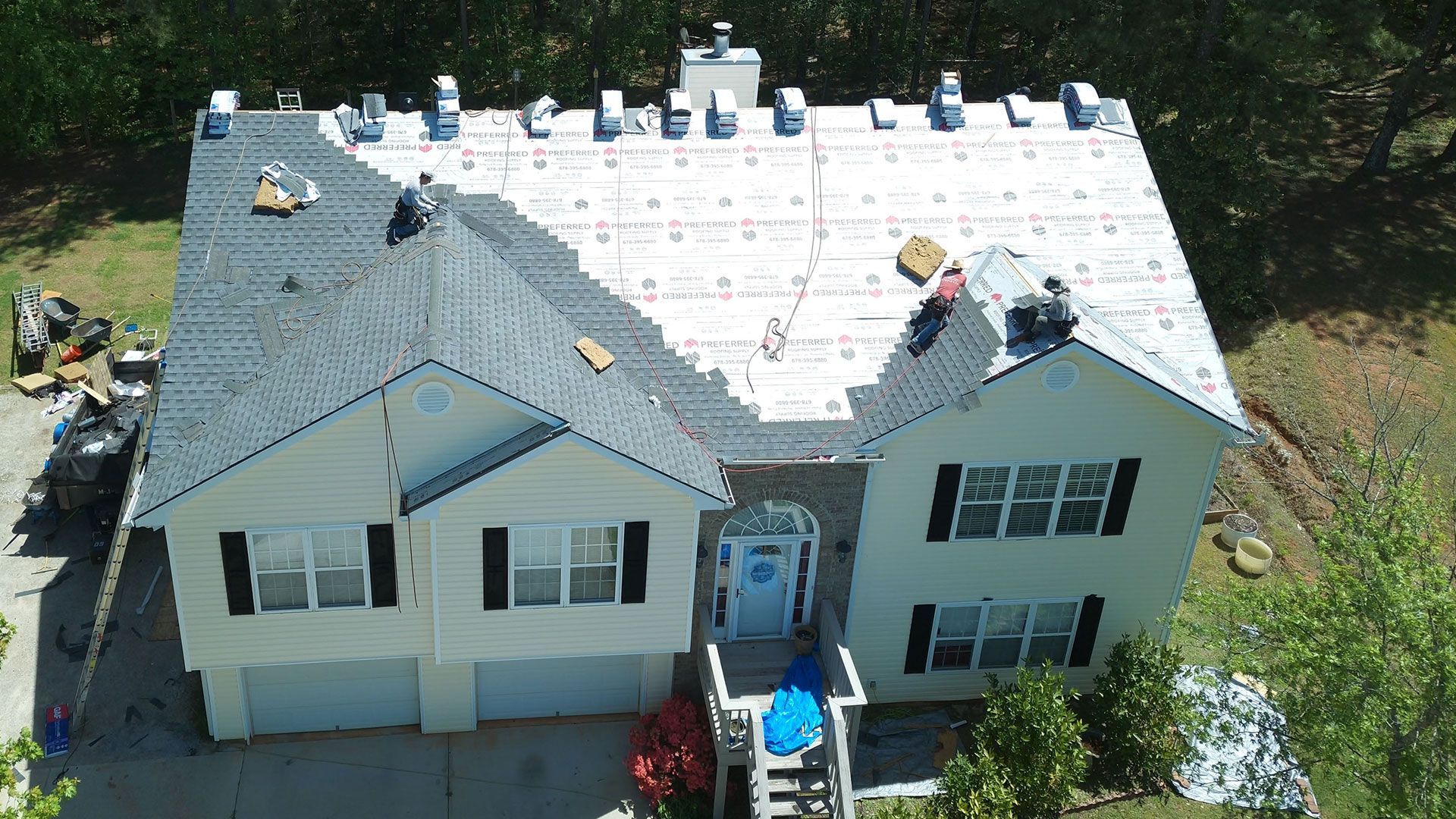 An aerial view of a house with a new roof being installed.
