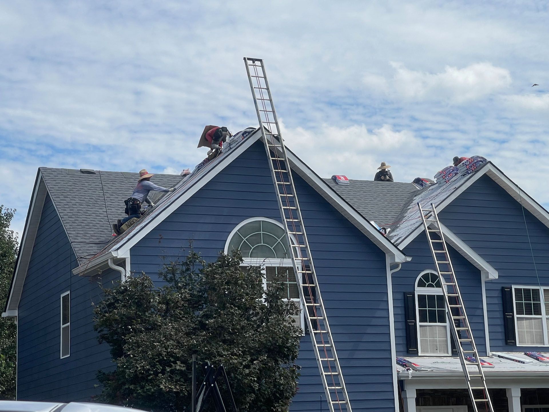 Two ladders are attached to the roof of a blue house