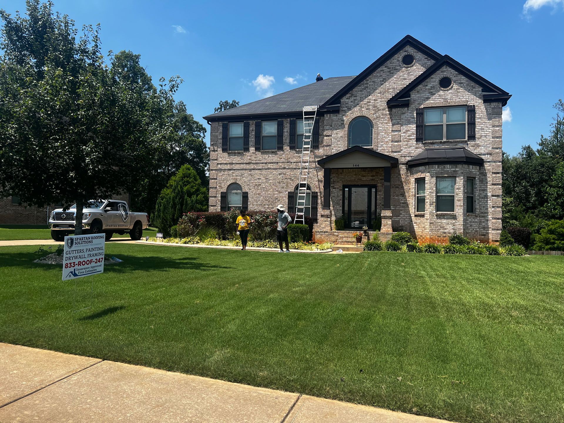 A large brick house with a sign in front of it