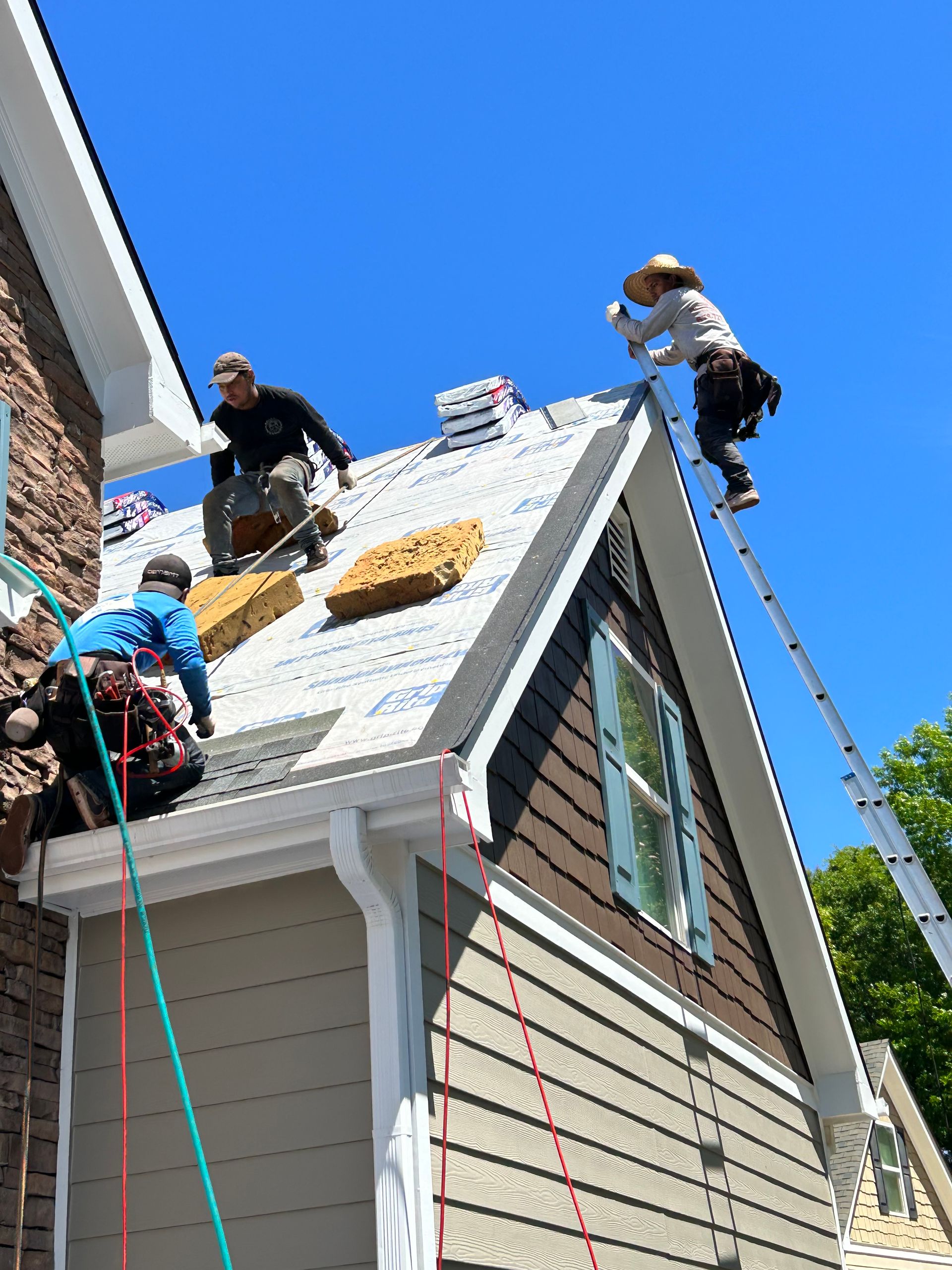 A group of people are working on the roof of a house.