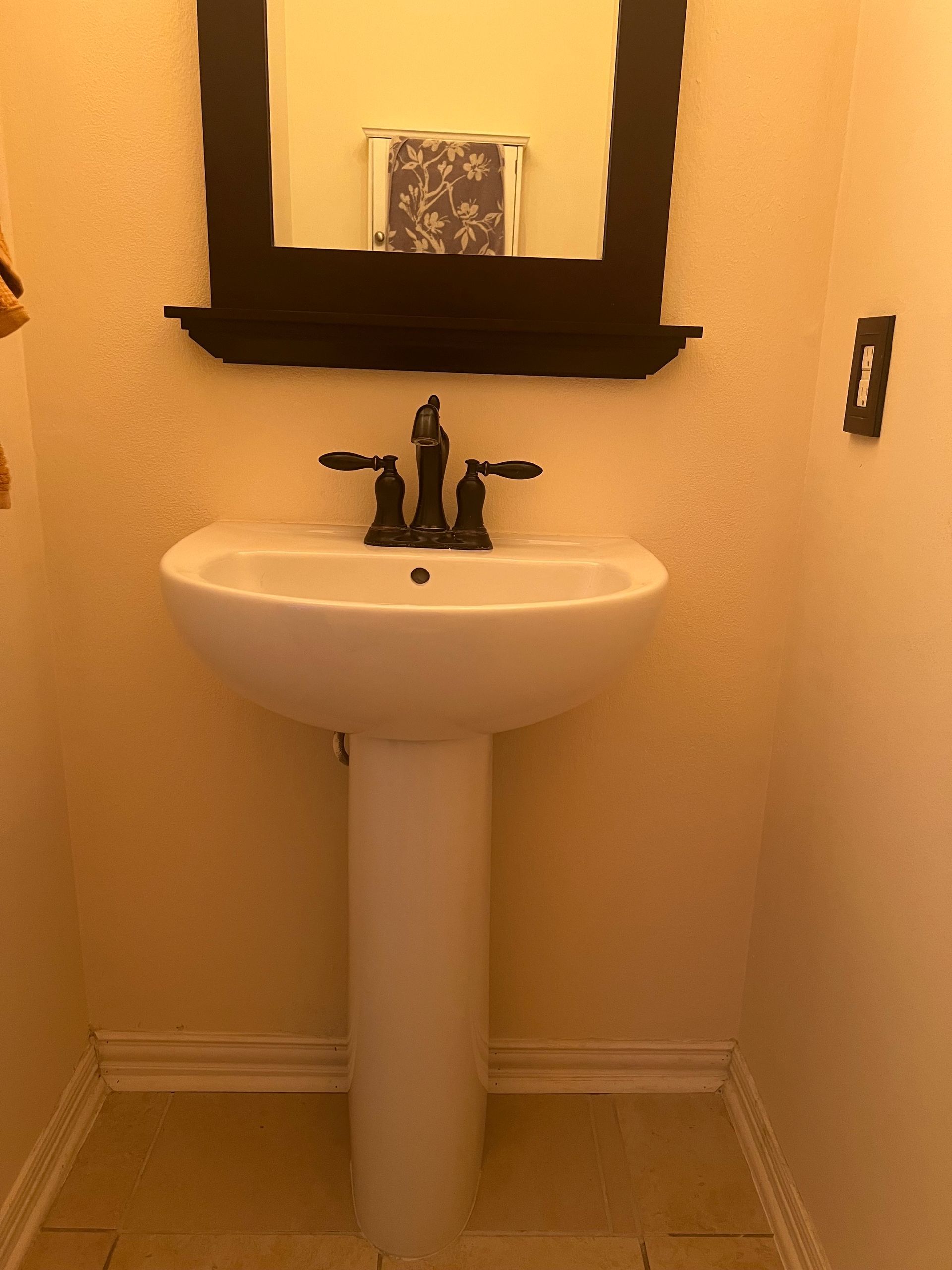 A bathroom with a pedestal sink and a mirror.
