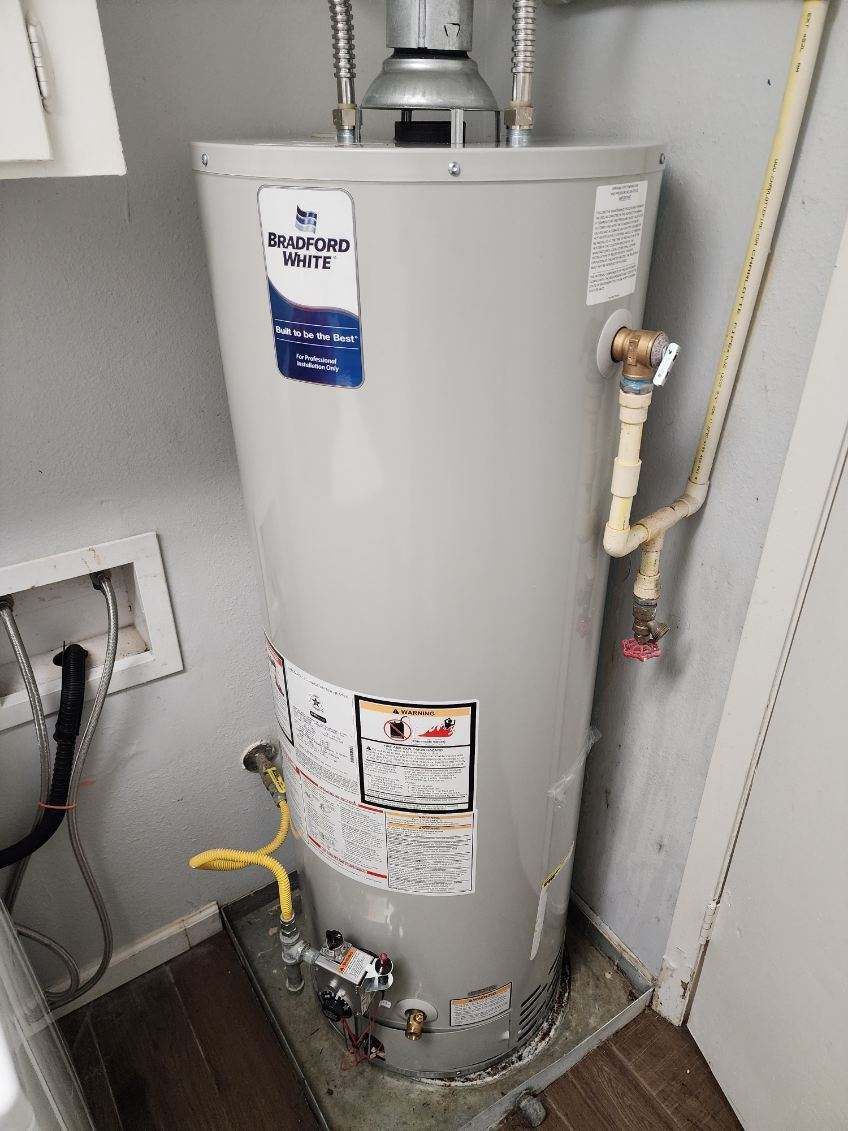 A gas water heater is sitting on the floor in a room.