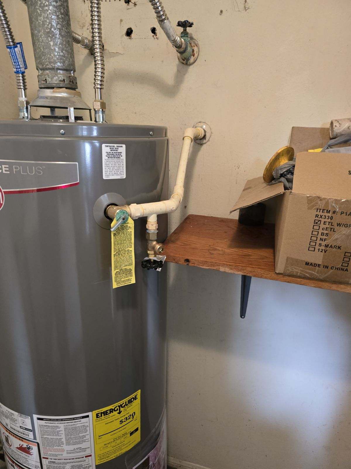 A water heater is sitting on top of a wooden shelf in a room.