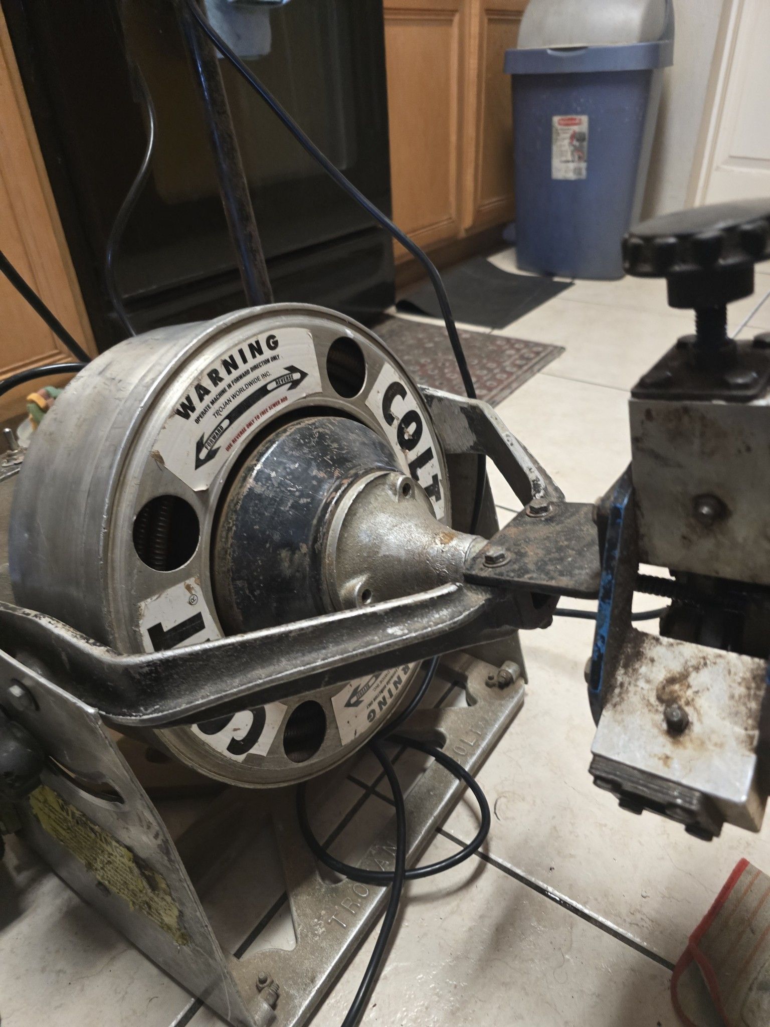 A machine is sitting on a tiled floor next to a trash can.
