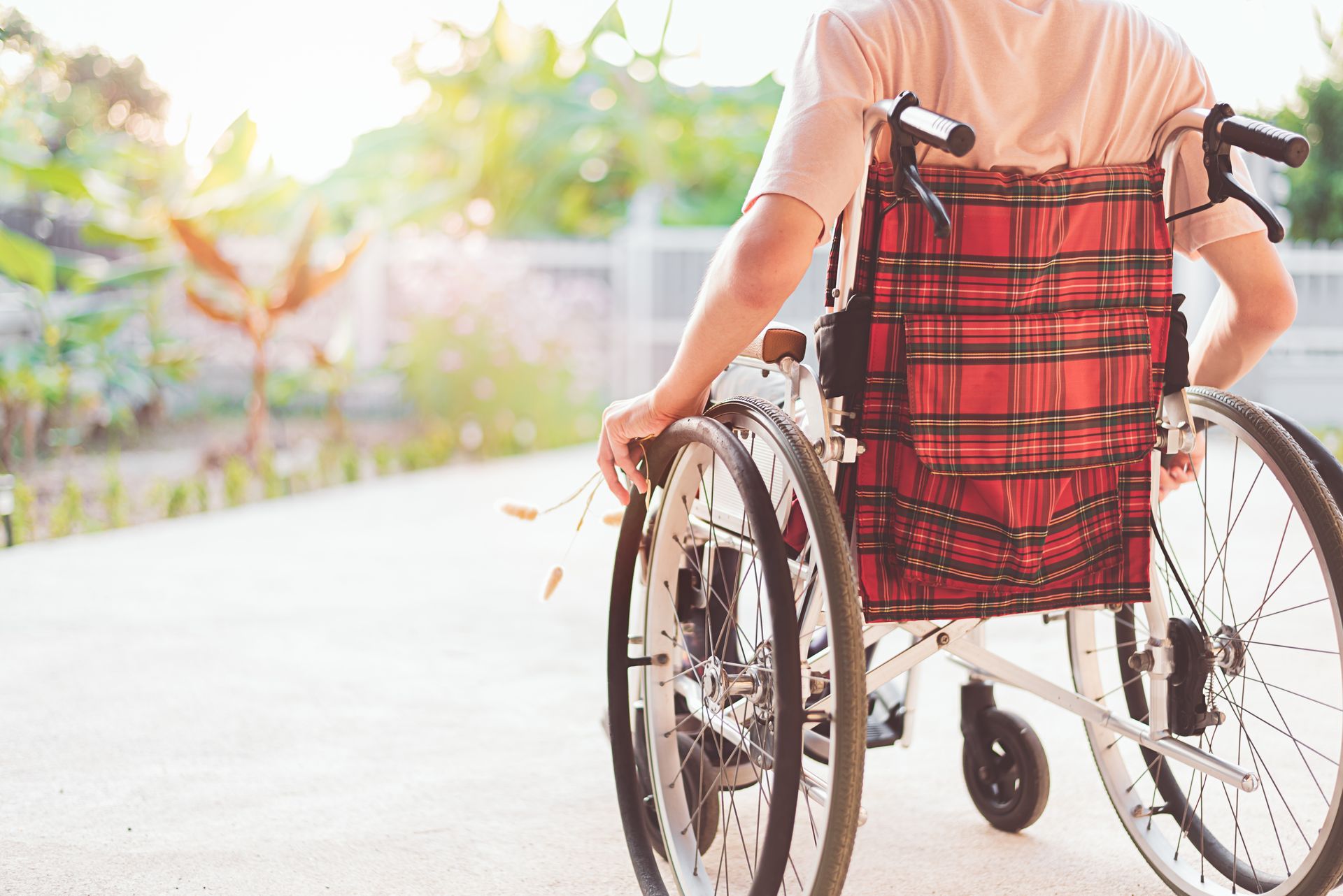 Man in wheelchair with face not visible - rear view with plaid wheelchair backing design