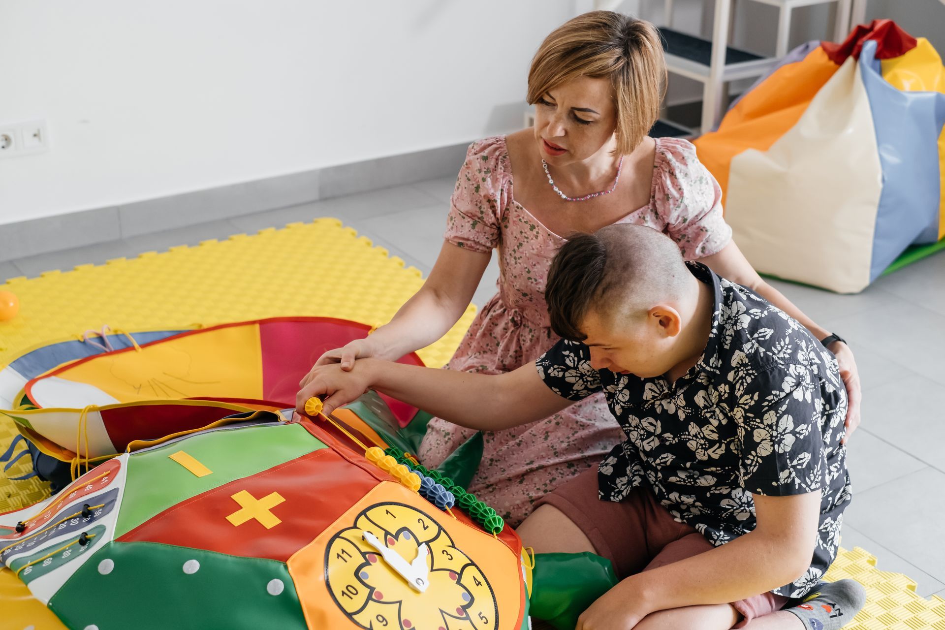 Female support worker sitting and engaging in activities with a teenager with Cerebral Palsy
