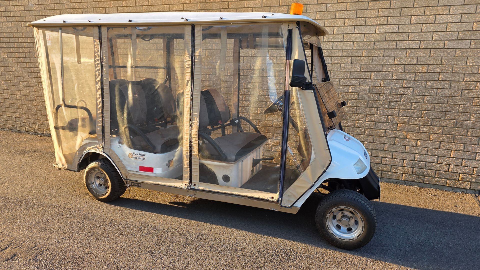 Small white utility cart with clear side panels parked beside a brick wall — Lift It Equipment in Central Coast Region, NSW