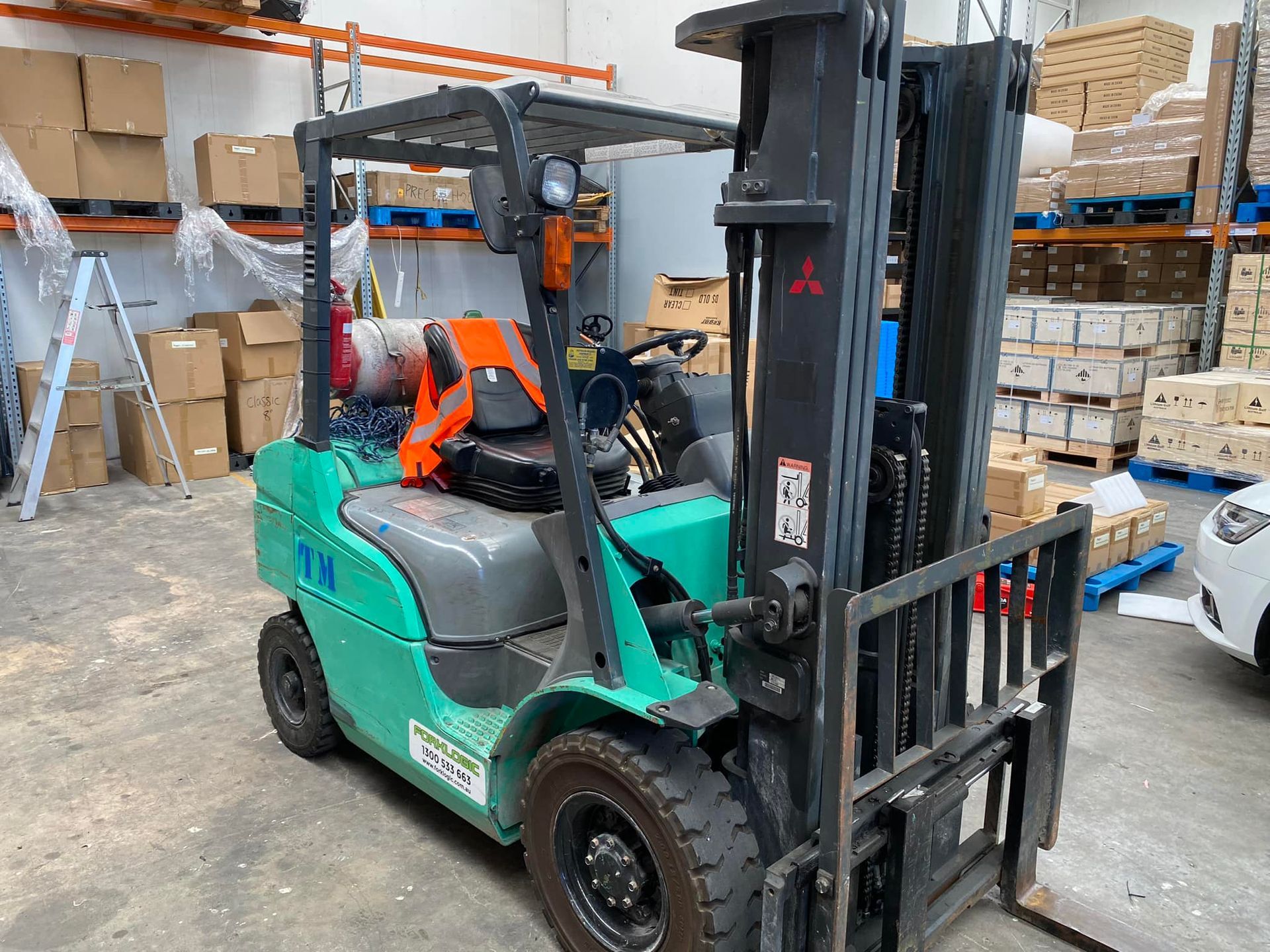 Green Mitsubishi Forklift Parked in a Warehouse Aisle — Lift It Equipment in Tuggerah, NSW