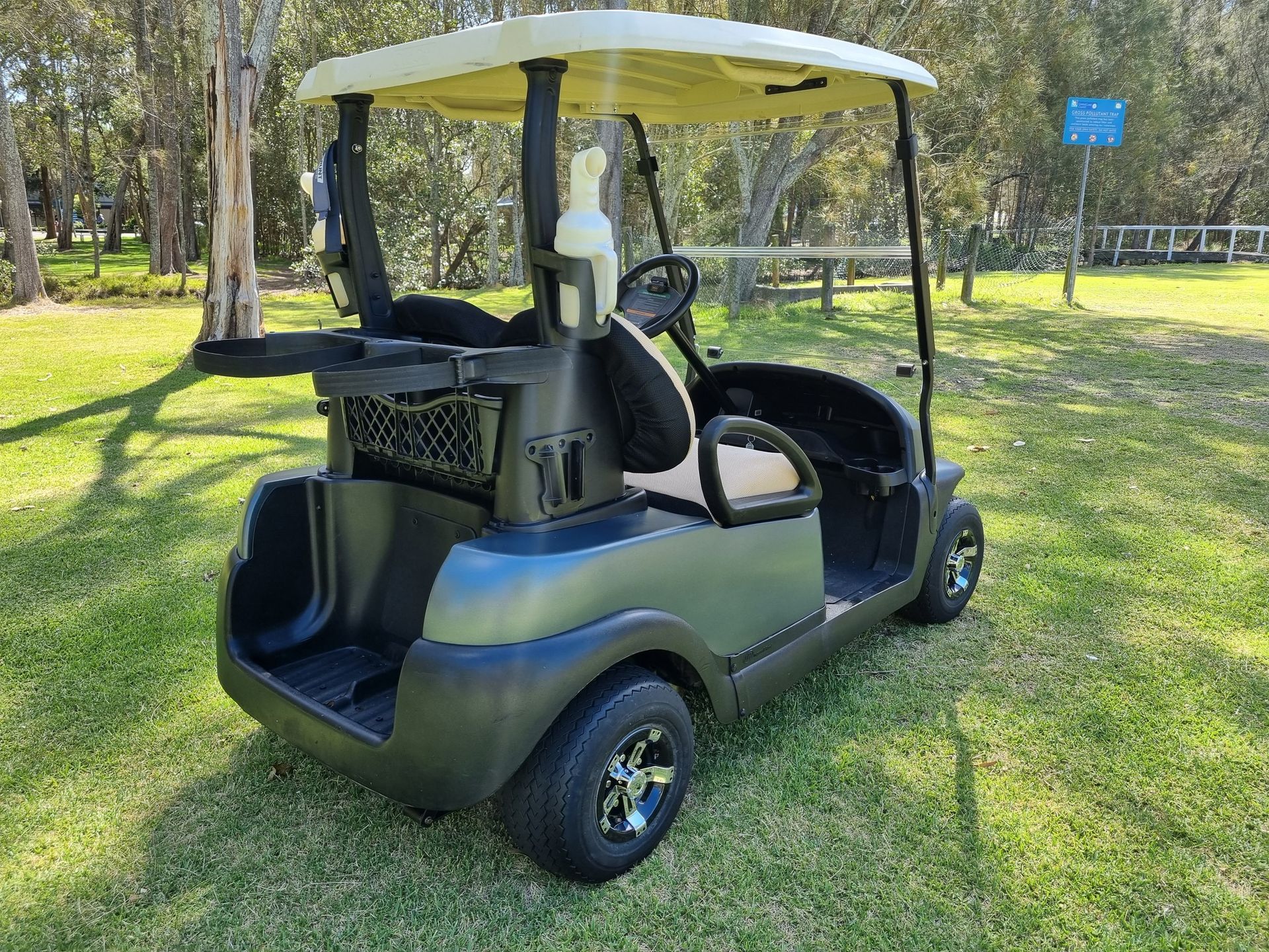 Black Golf Cart Parked on Grass in a Sunny Wooded Area — Lift It Equipment in Tuggerah, NSW