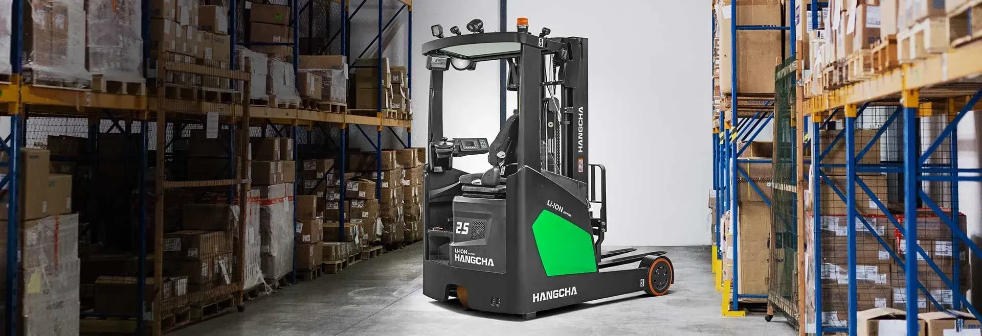 Black Forklift in a Warehouse Aisle Between Tall Shelves and Stacked Boxes — Lift It Equipment in Tuggerah, NSW