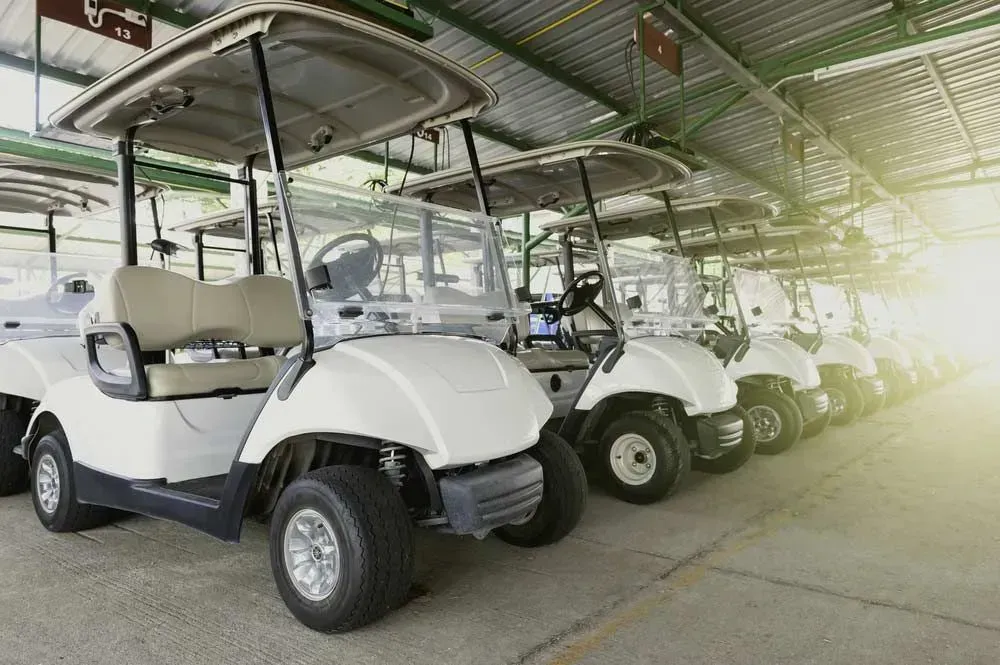 Row of White Golf Carts Parked Under a Covered Structure — Lift It Equipment in Tuggerah, NSW