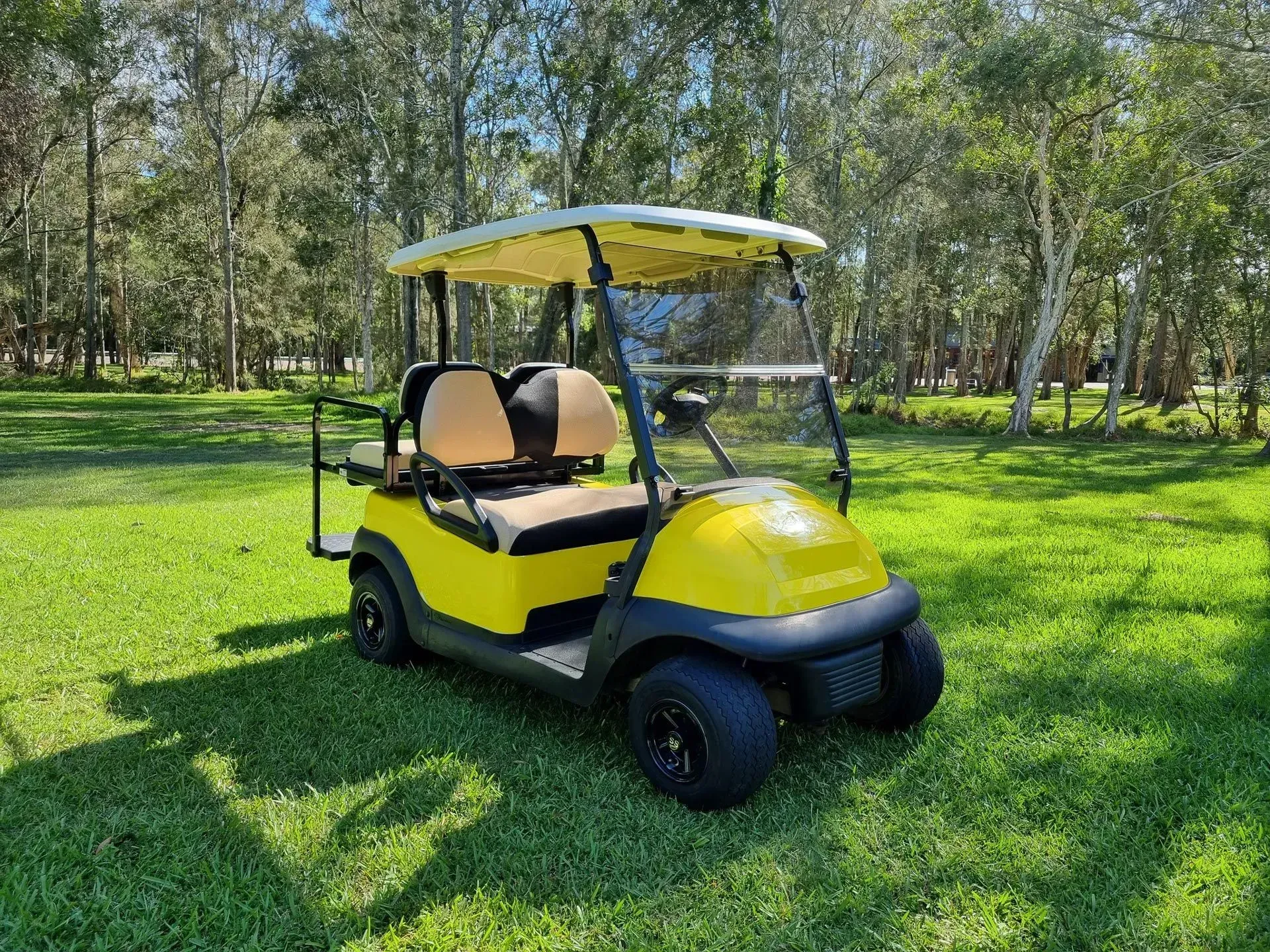 Yellow Golf Cart Parked on Grass in a Sunny Park With Trees — Lift It Equipment in Central Coast Region, NSW