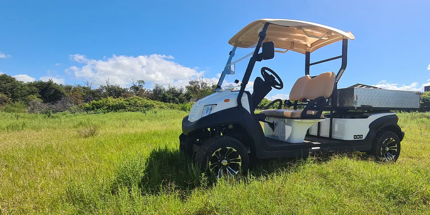 White Golf Cart With Tan Canopy Parked in a Sunny Grassy Field — Lift It Equipment in Sydney, NSW