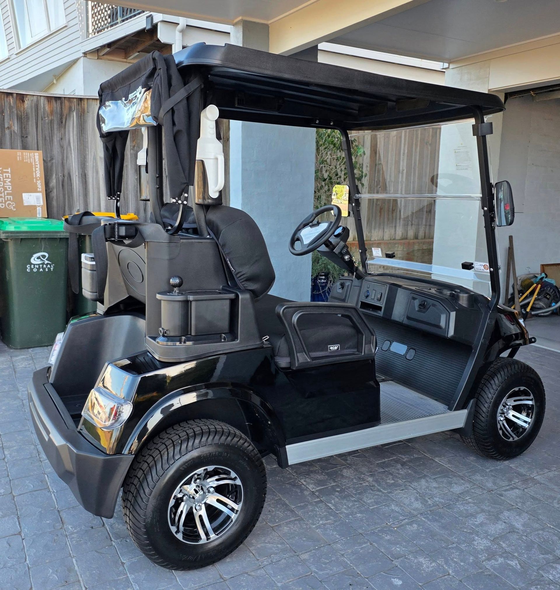 Black Golf Cart With Canopy Parked in a Driveway Beside Bins and a House — Lift It Equipment in Tuggerah, NSW