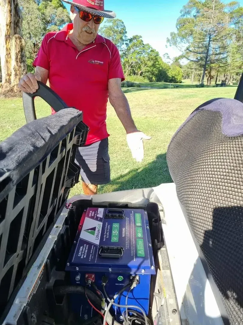 Person in Red Shirt and Hat Checks a Battery Setup — Lift It Equipment in Tuggerah, NSW