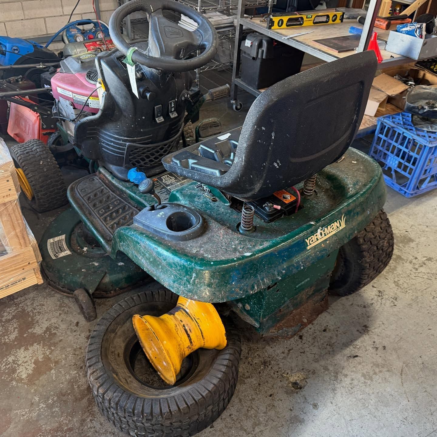 Green Riding Lawn Mower With a Black Seat and Yellow Wheel — Lift It Equipment in Tuggerah, NSW