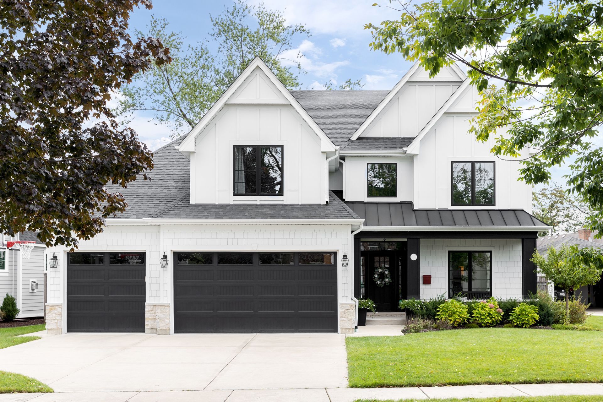 A White House With Black Garage Doors and a Black Roof
