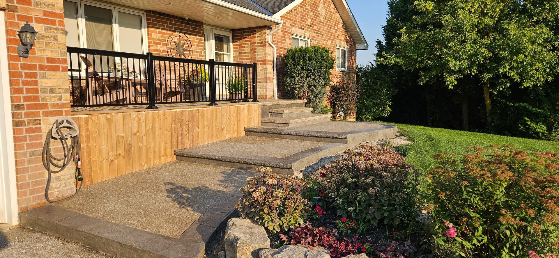 A set of concrete steps leading up to a porch with a canadian flag in the background.