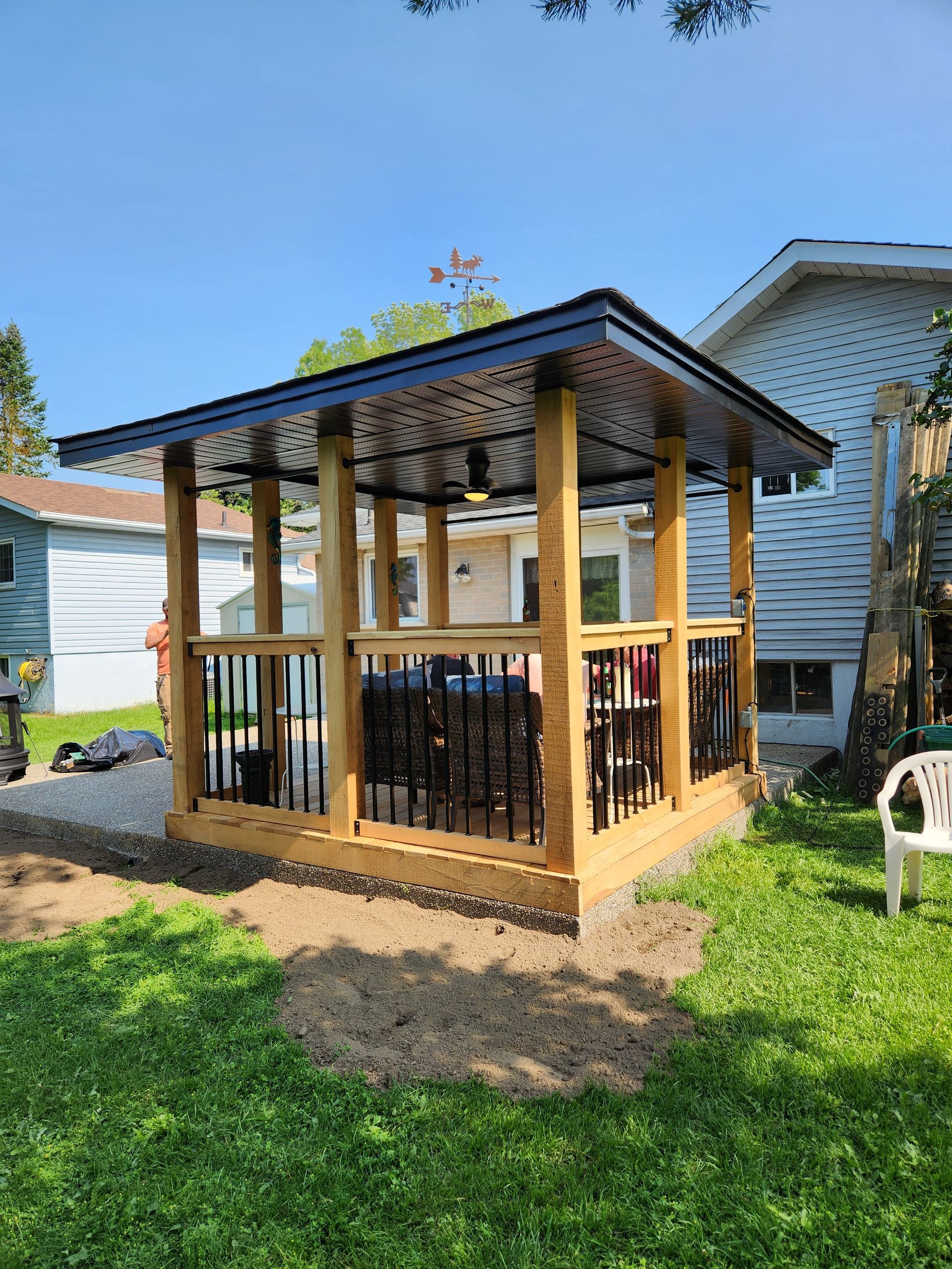 A wooden gazebo in the backyard of a house.