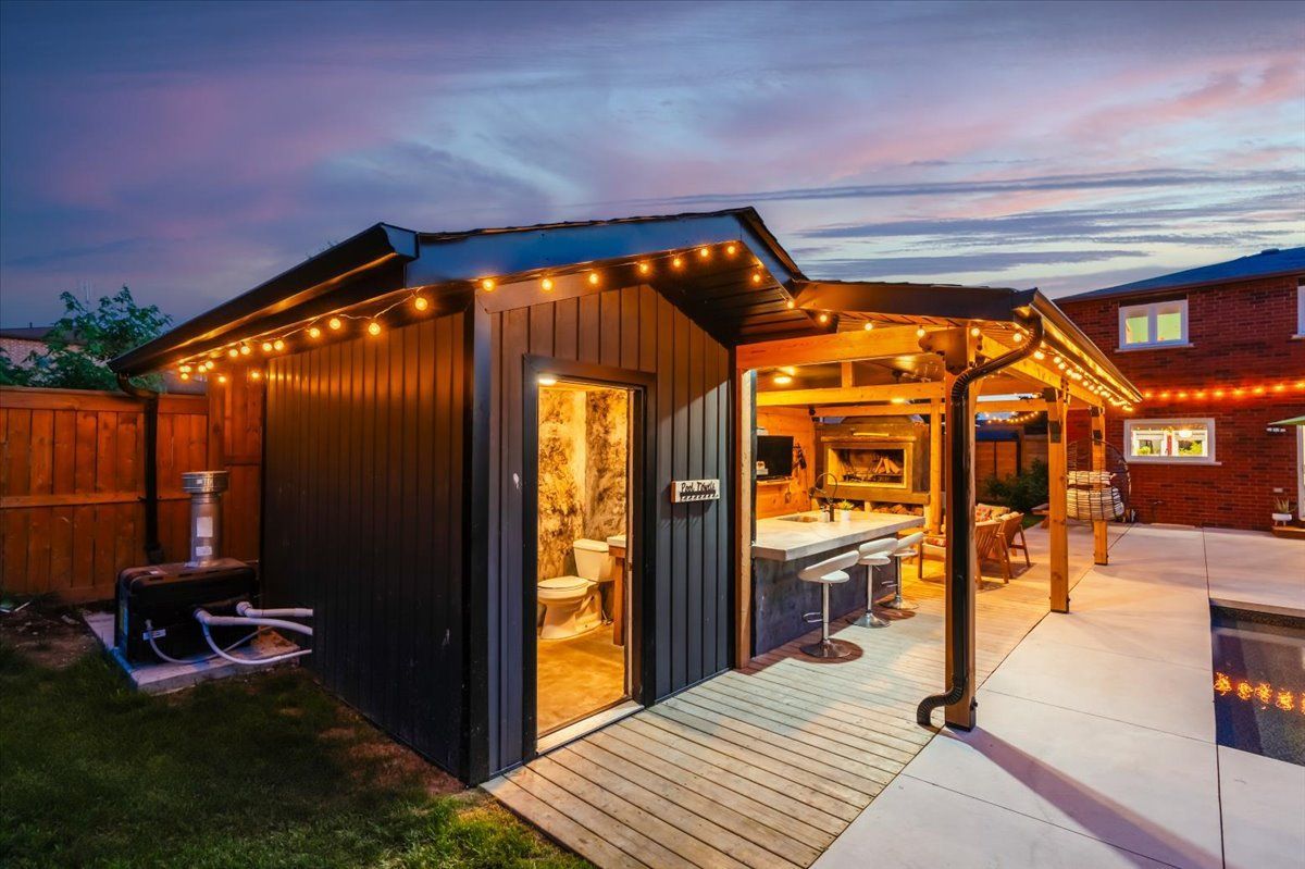 A shed with a kitchen and a bar in the backyard at night.