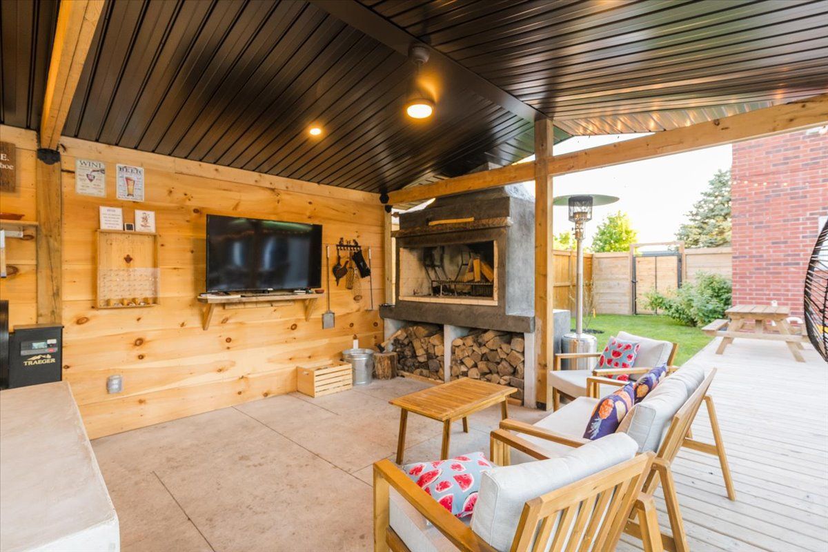 A patio with chairs , a table , a television and a fireplace.